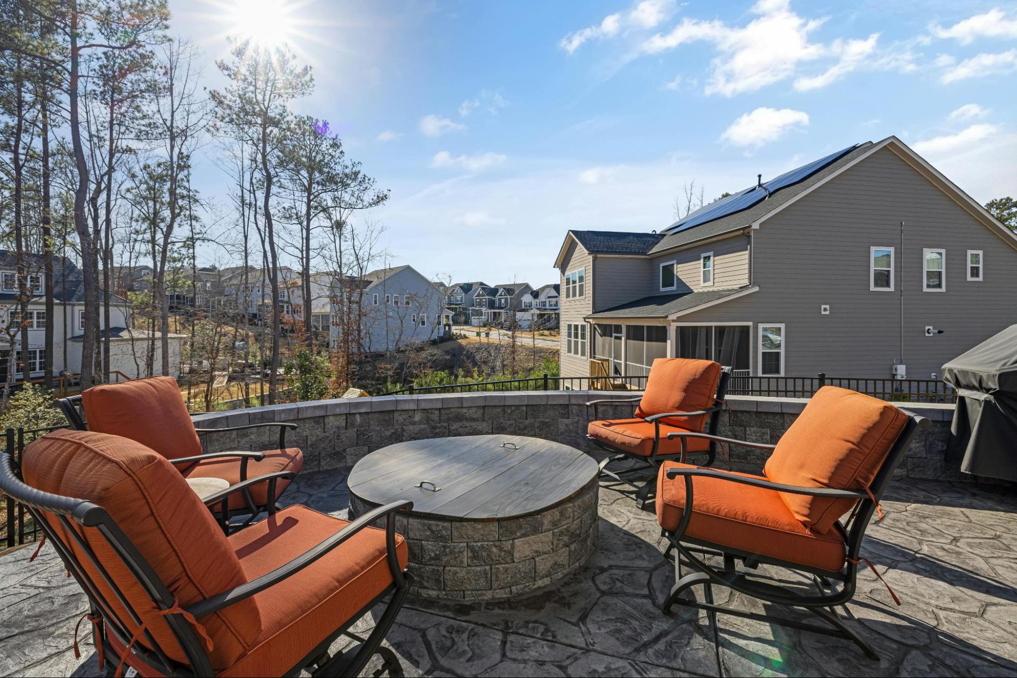 A covered, outdoor fire pit with chairs around it.