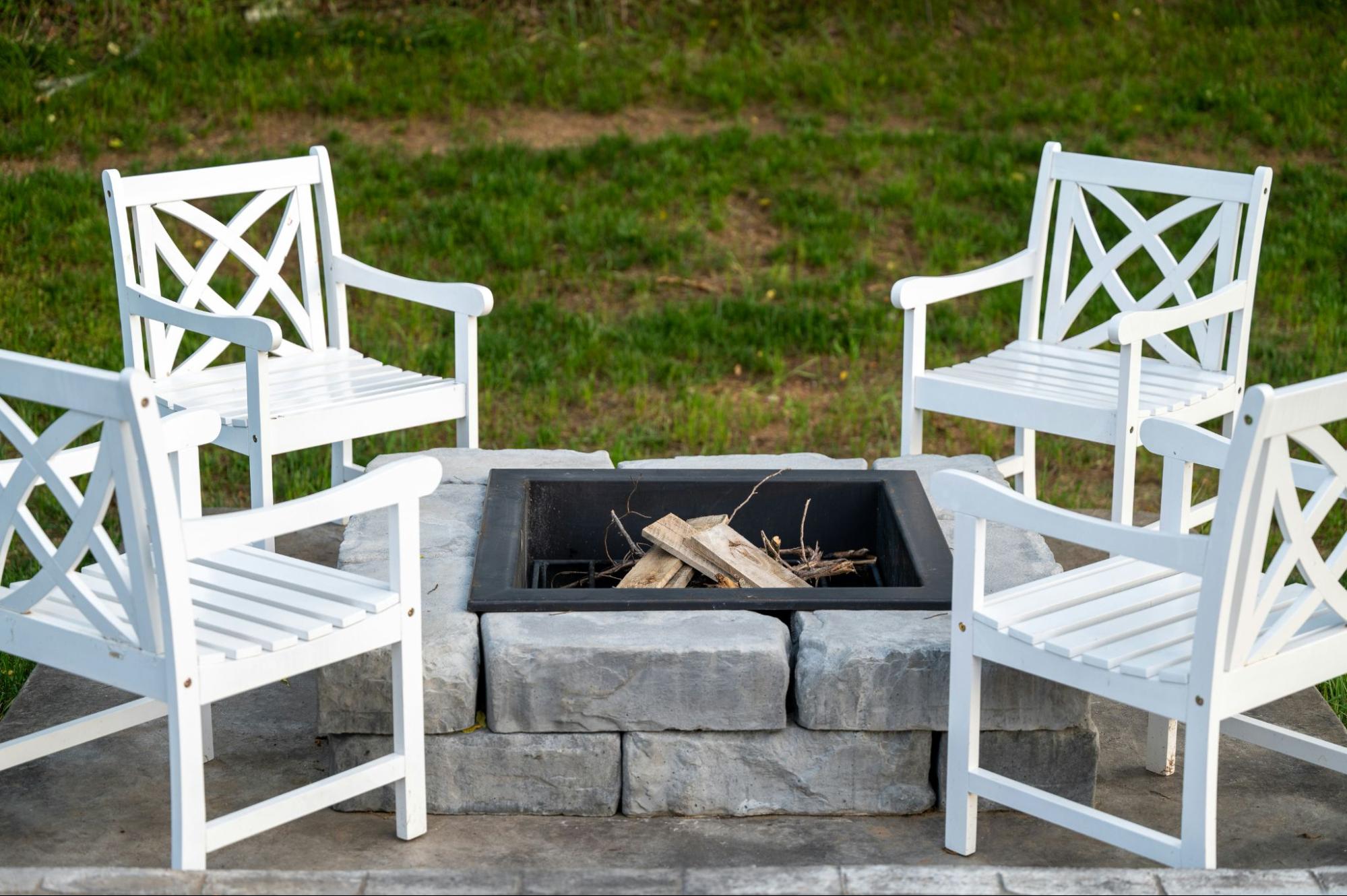 A simple, natural stone fire pit with chairs around it.