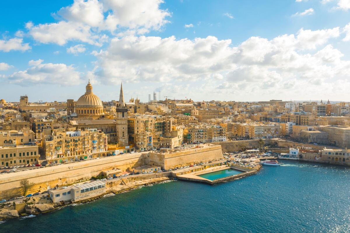 Illustrated aerial view of a sustainable, modern Maltese coastal city with clear blue water and traditional boats, symbolizing green finance and the blue economy.