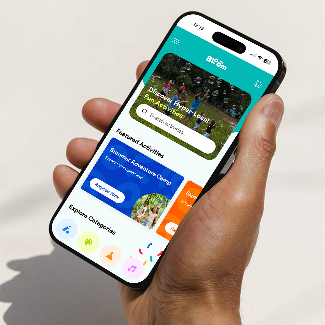 A hand holding a smartphone displaying the Bloom app interface with colourful cards for classes, events, and recommendations.