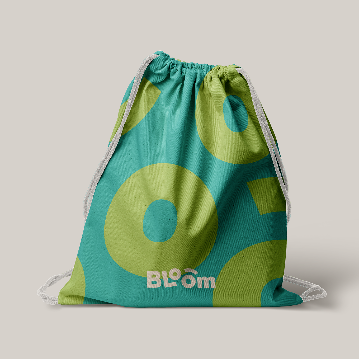 A drawstring fabric bag featuring the Bloom logo and abstract graphic ‘O’ shapes in teal and yellow.
