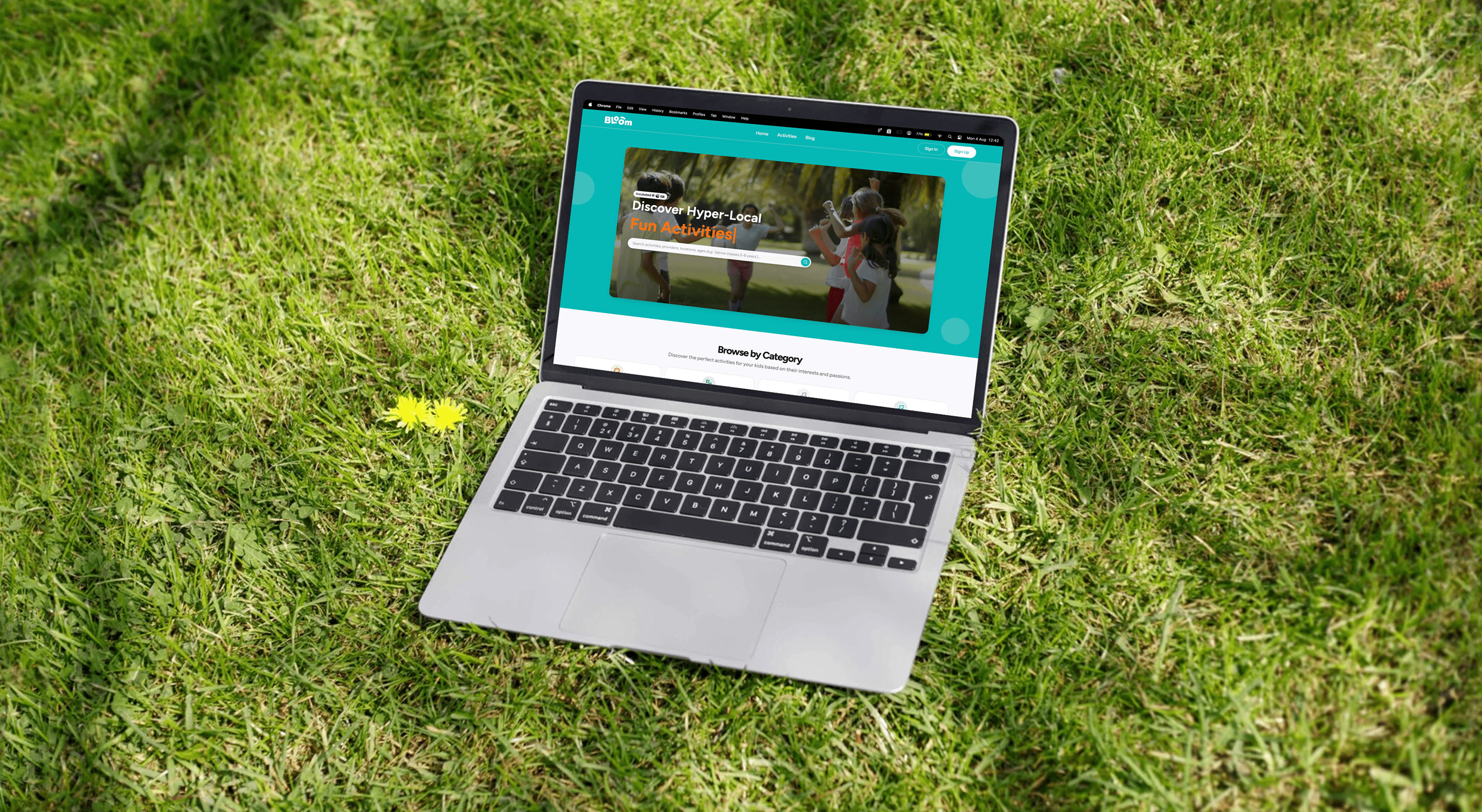 An open laptop placed on grass displaying the Bloom website homepage.