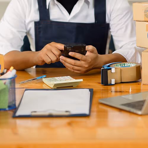 A person sat a table working on their phone.