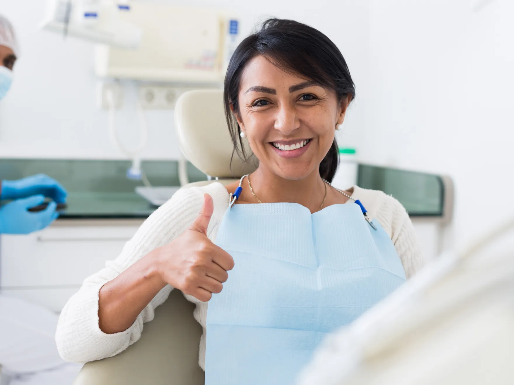 a woman in a dentist chair giving a thumbs up