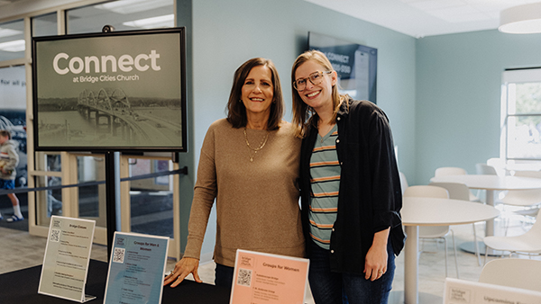 two women smiling next to a connect sign