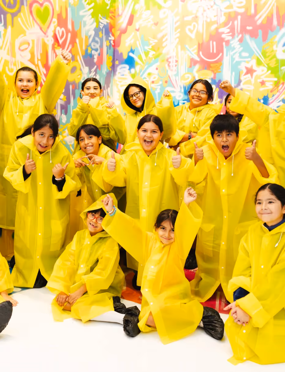 Group of kids in yellow ponchos cheering during a birthday party