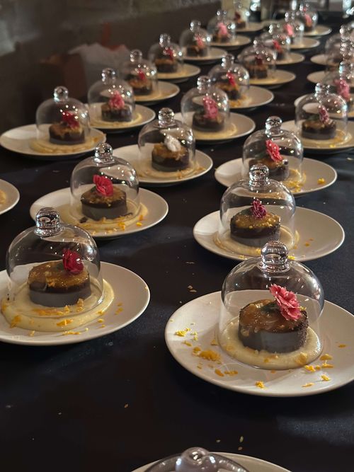 Grand Marnier dessert cakes displayed under glass cloches at Chef Joann Catering’s red-draped luxury dinner event.