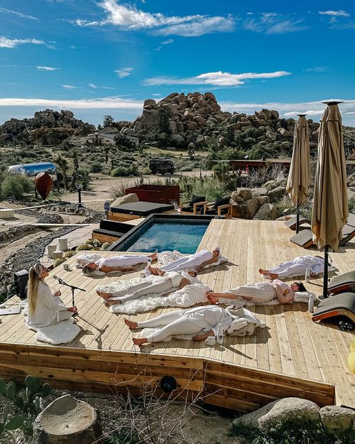 Facilitator speaking at the Starseed Awakening retreat in Joshua Tree, with attendees resting on the ground wrapped in white blankets, as Chef Joann Catering nourished guests with mindful meals throughout their transformative experience.