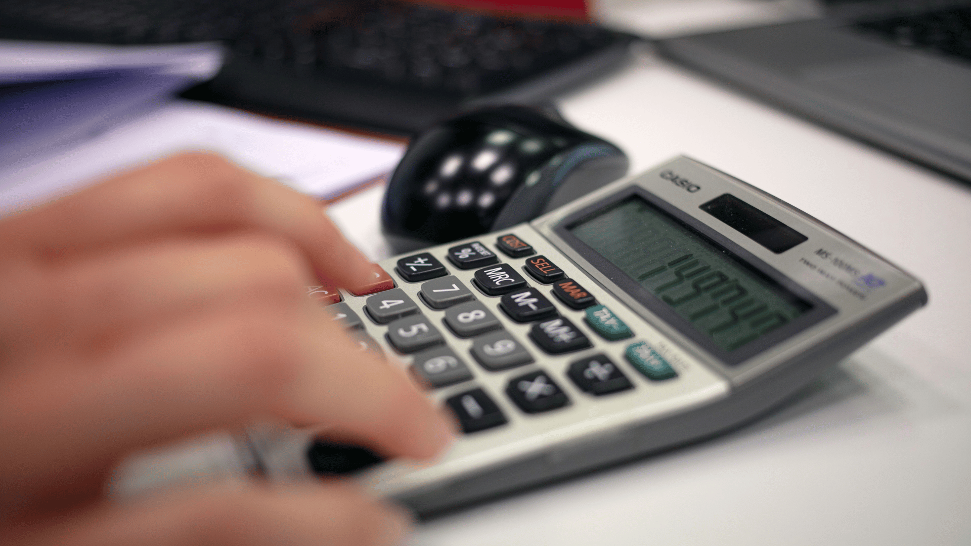 Hand using the calculator on a desk