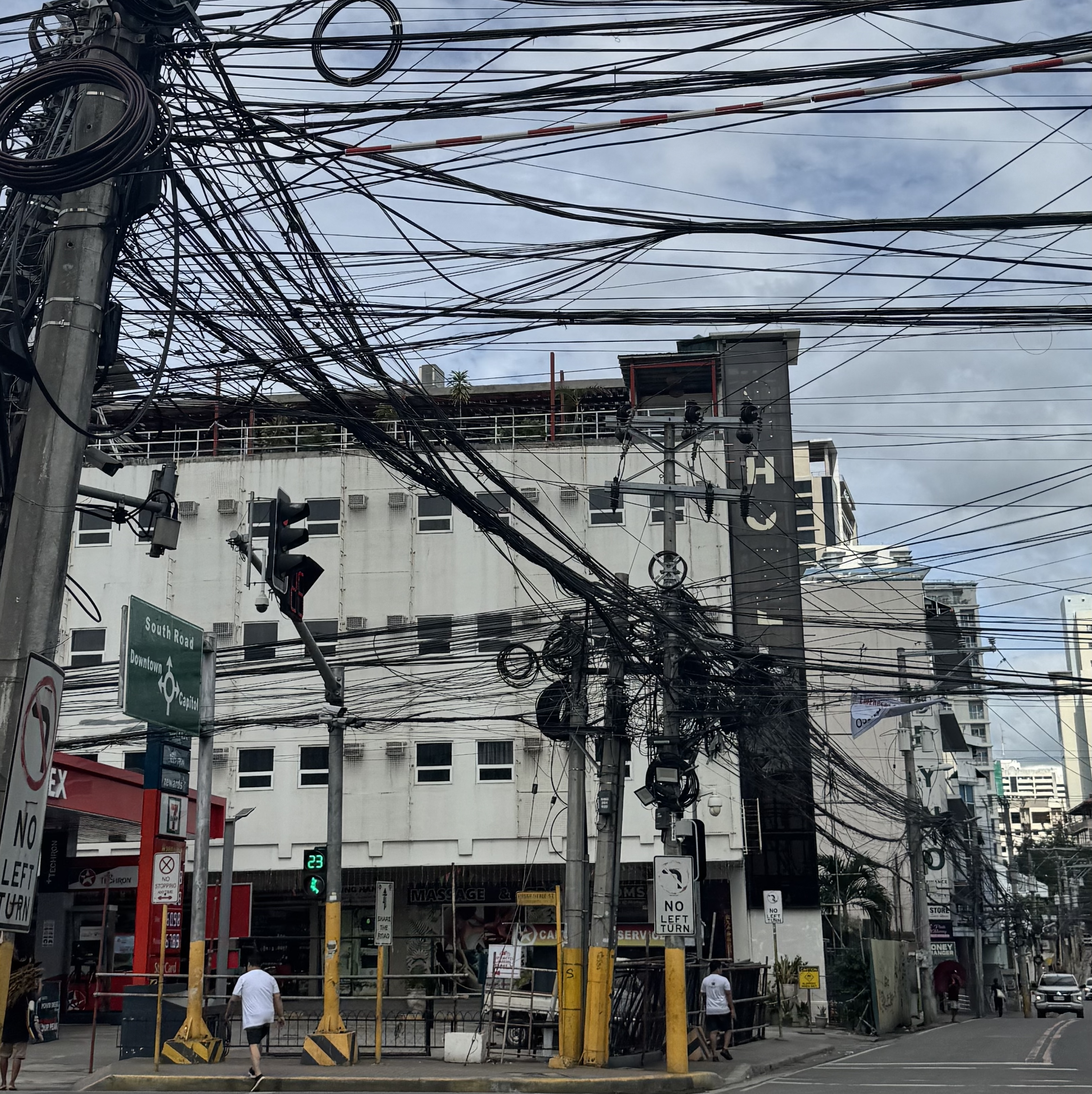 Crossroads in city centre, Philippines with overhead cables hanging from telegraph poles.