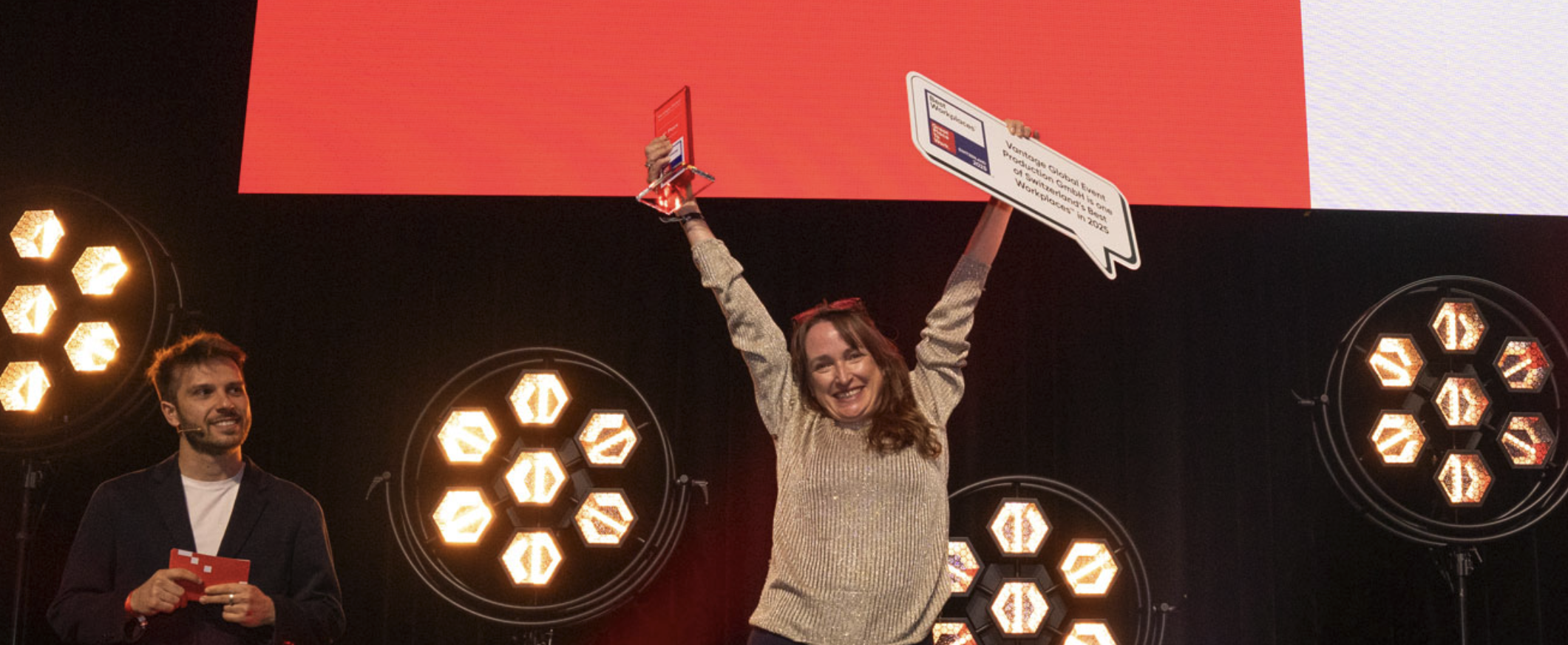 On stage, women from Vantage raises the Great Place to Work trophy and sign above her head.