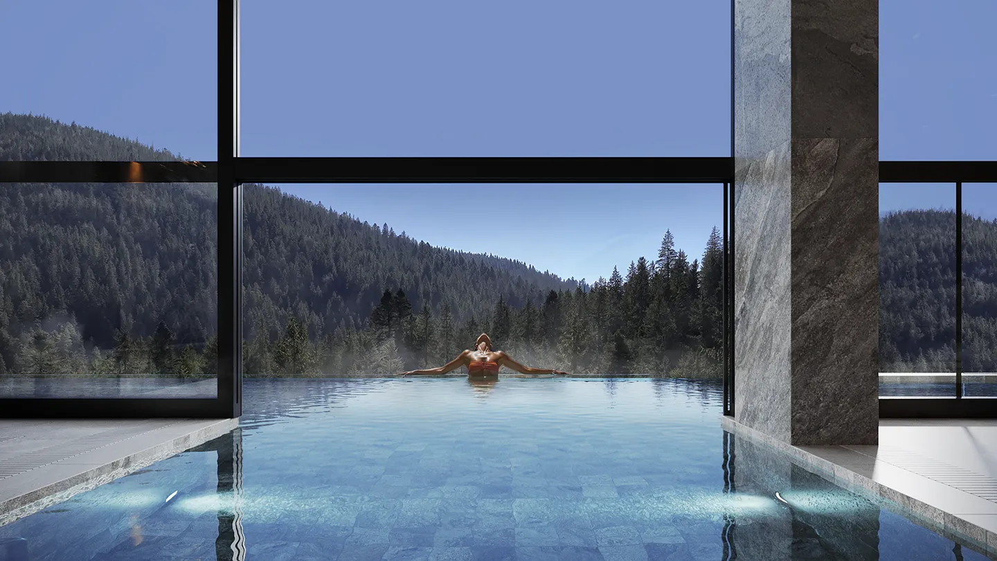 Жінка в червоному купальнику розслабляється на краю басейну з видом на лісисті гори.