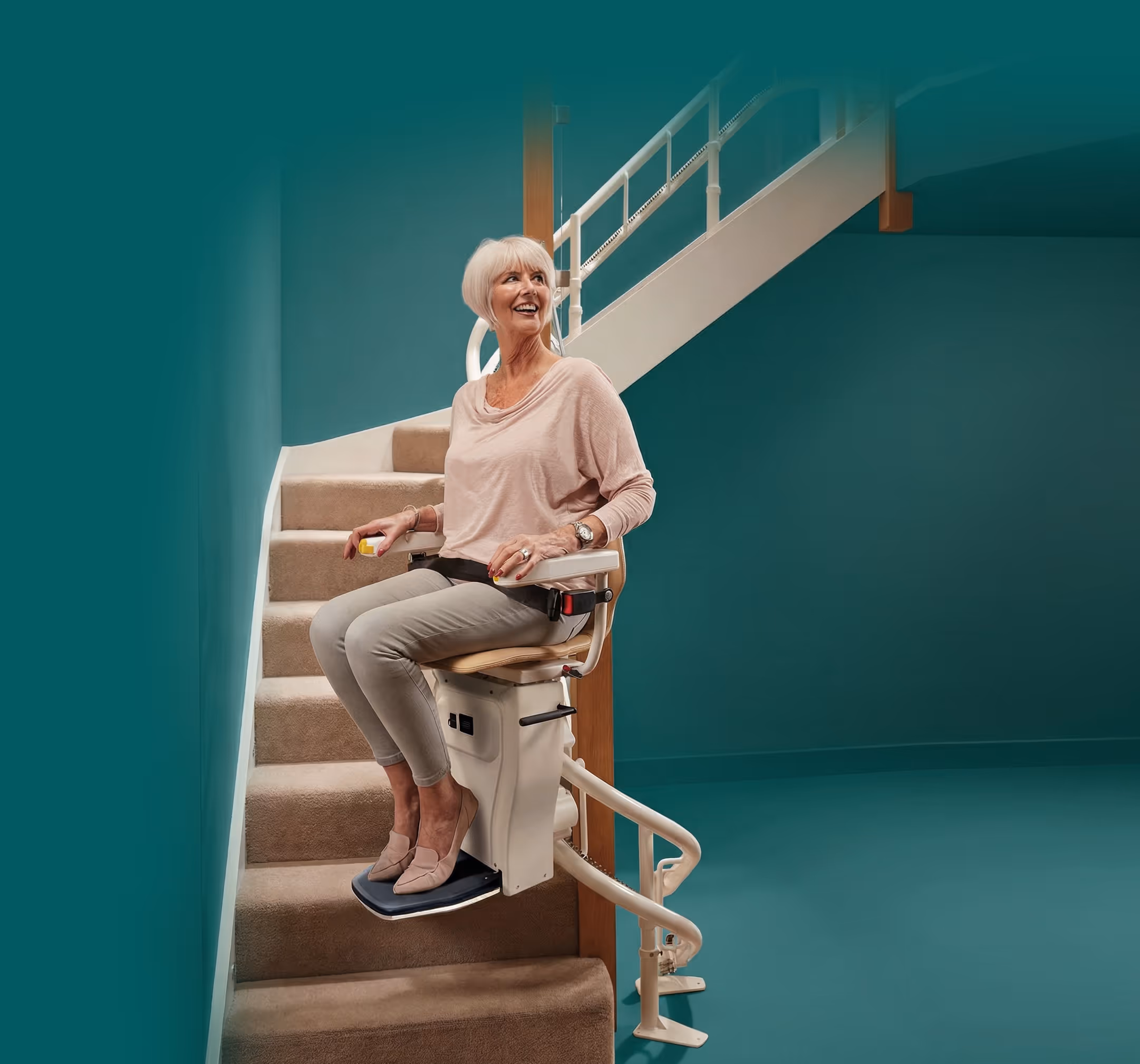 Smiling woman sitting on a Homelife stairlift chair on a curved stairway.