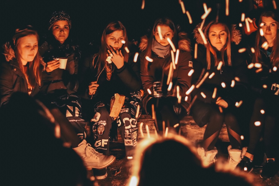 Youth group communing around a campfire, roasting marshmallows