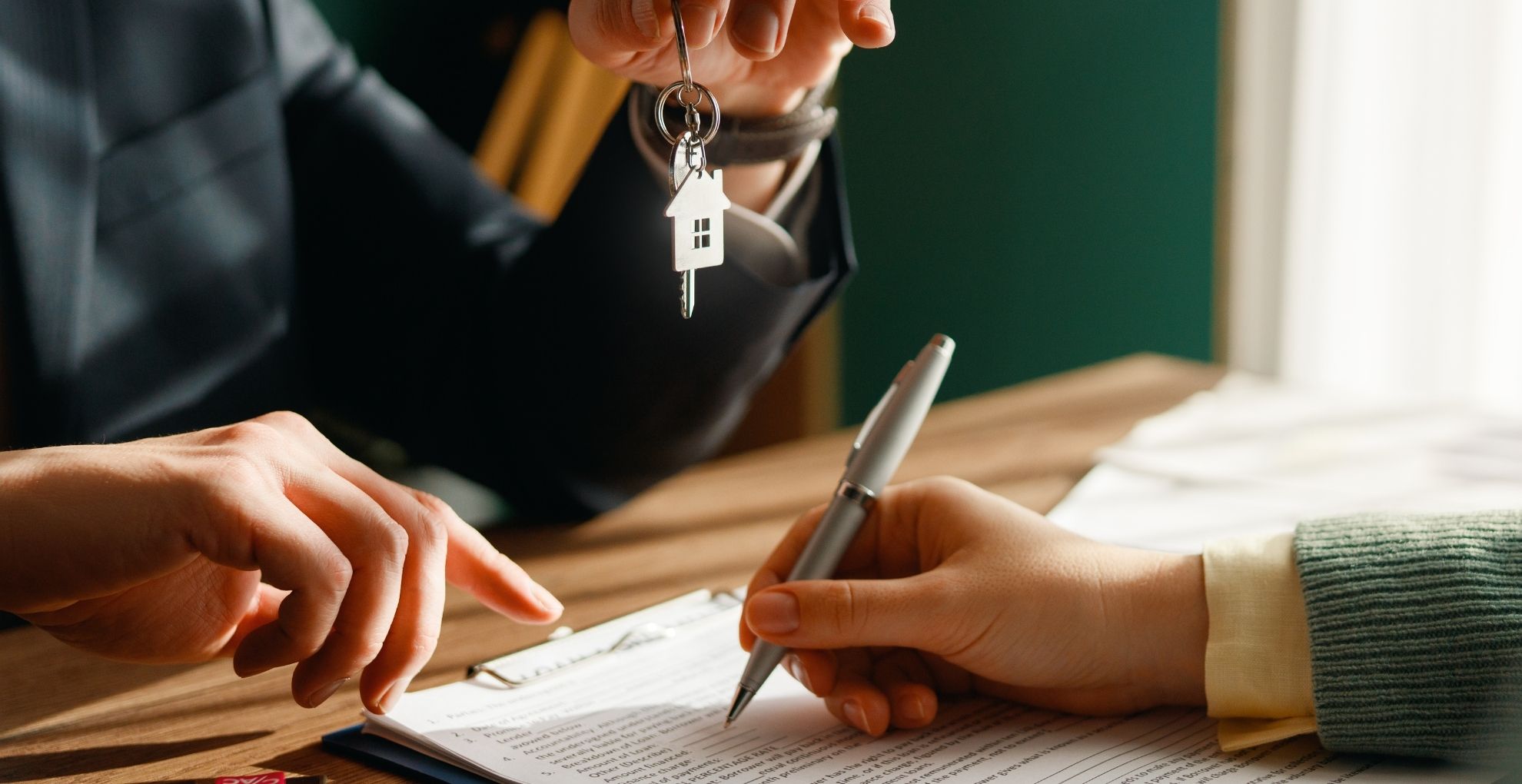 Hand tekent papier en hand geeft huissleutel