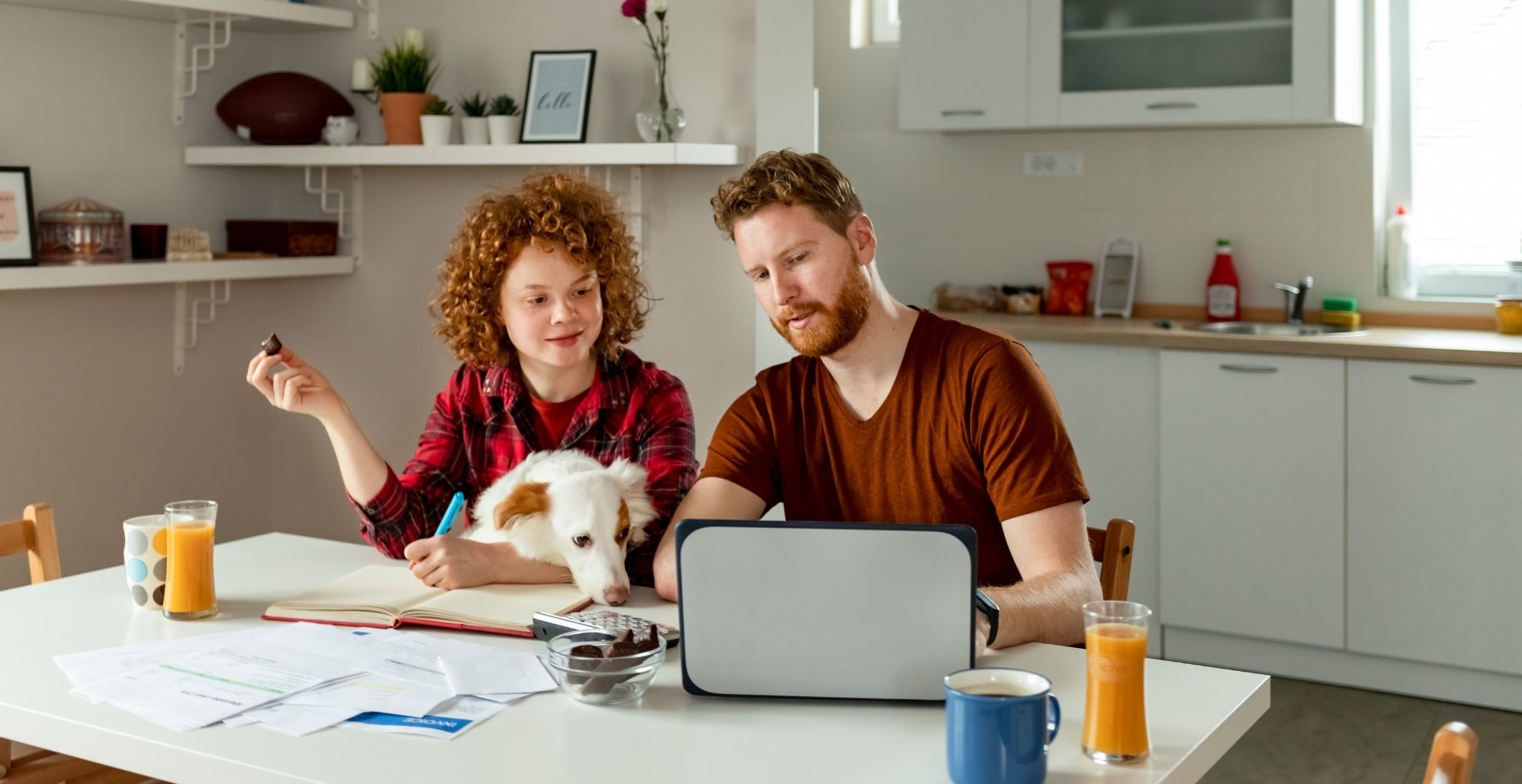 Man en vrouw aan keukentafel met laptop en papieren