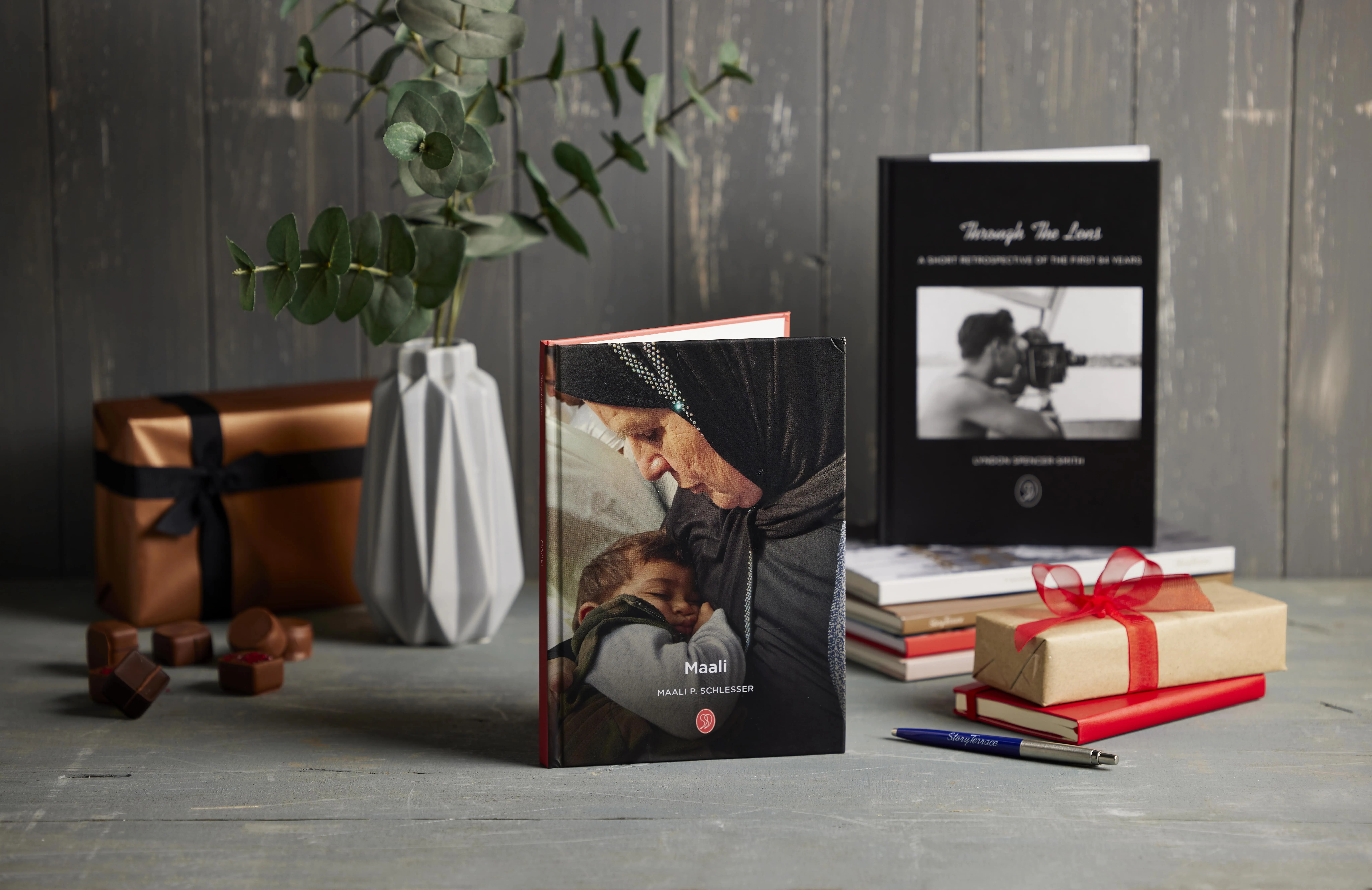 StoryTerrace - Books That Matter - Two books, gifts, and a vase on a wooden surface.