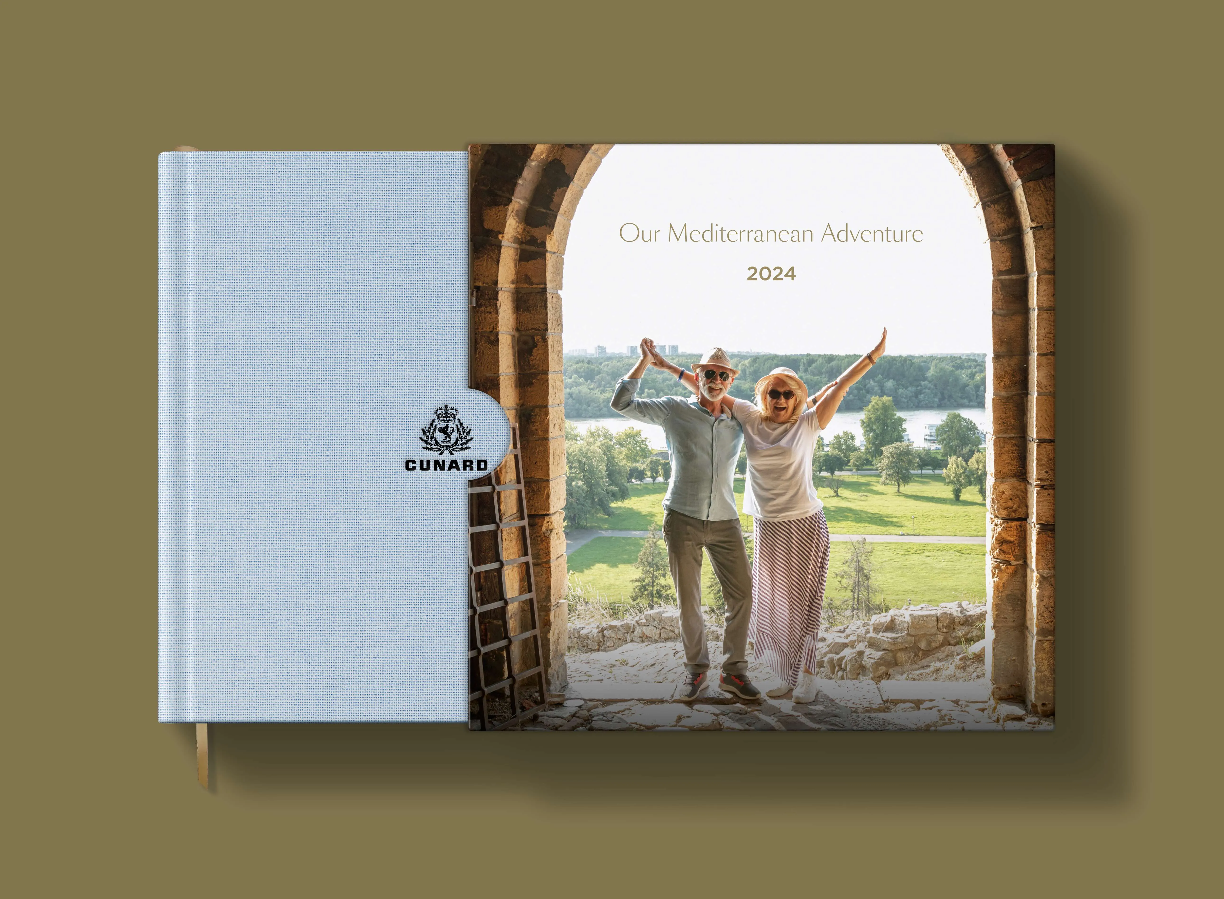 StoryTerrace - Books That Matter - Hardcover book titled "Our Mediterranean Adventure 2024" featuring a joyful couple posing under a stone archway with a scenic view,