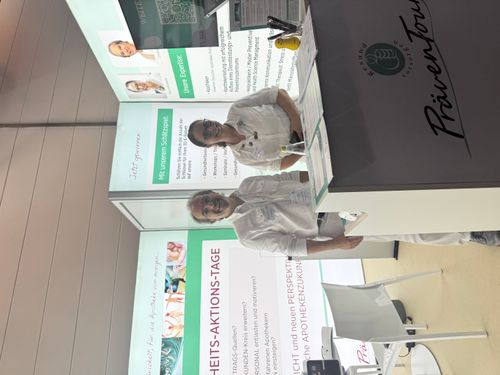 Eine Apothekerin hinter einer Theke nimmt das Rezept einer Kundin entgegen.