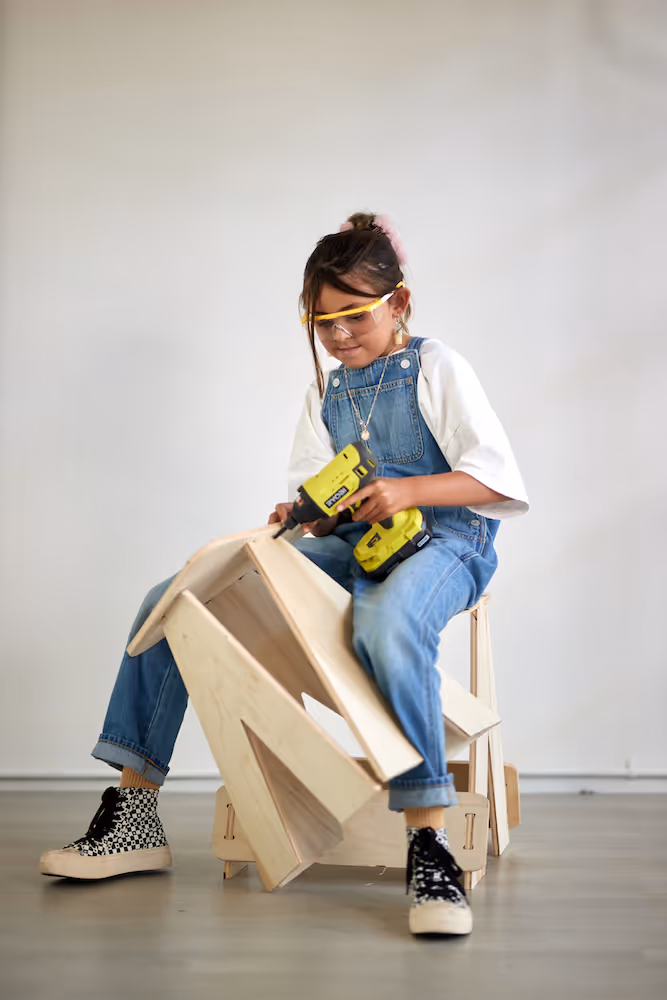 A young girl building a wooden chair