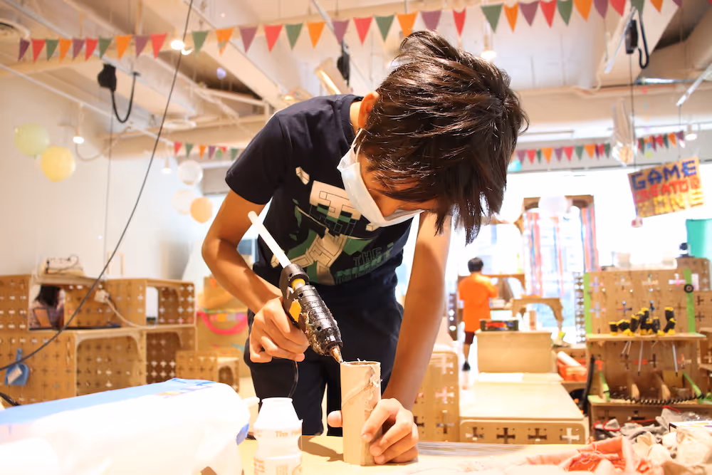 Kid using a glue gun and building prototyoe