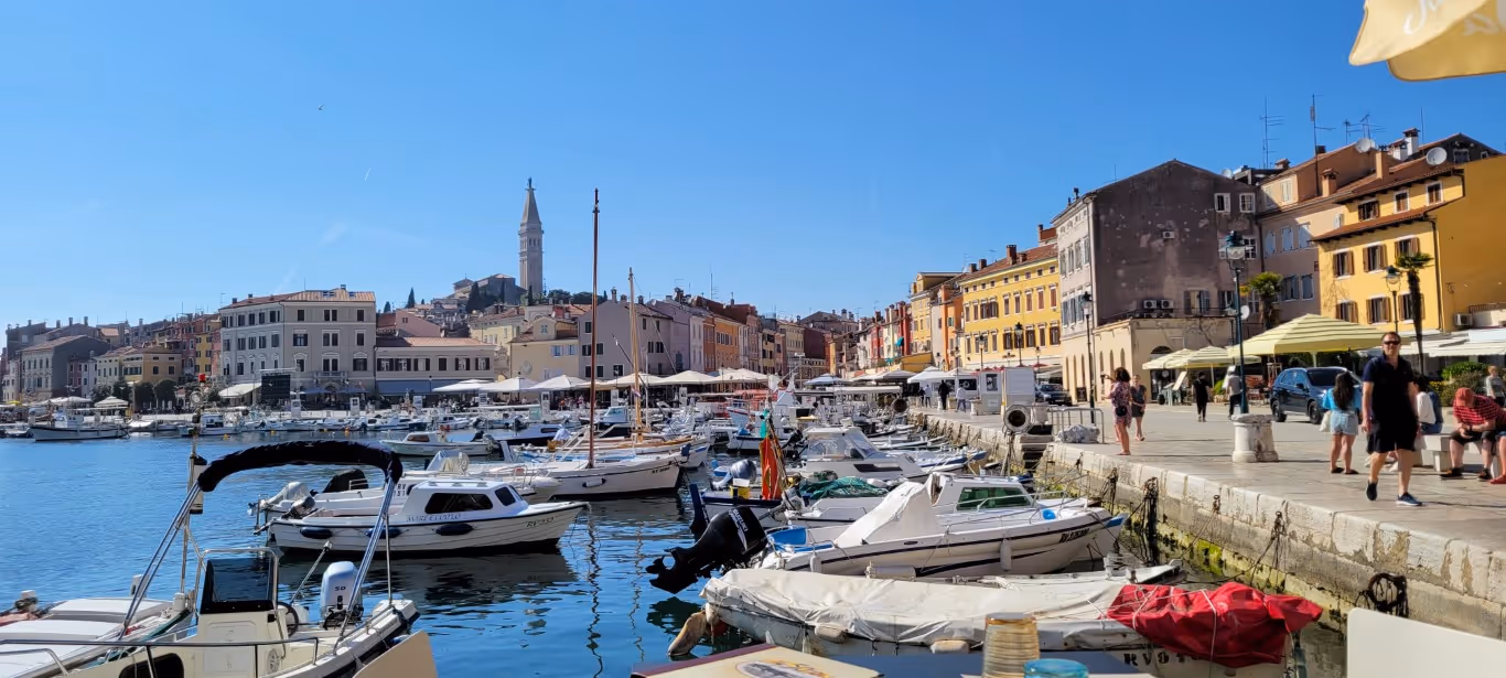 A bright coastal town in Croatia with small boats in the marina docked in front of Old Town.