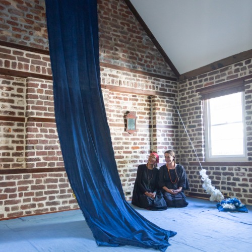 Indigo dyed linen hanging from the ceiling with artists