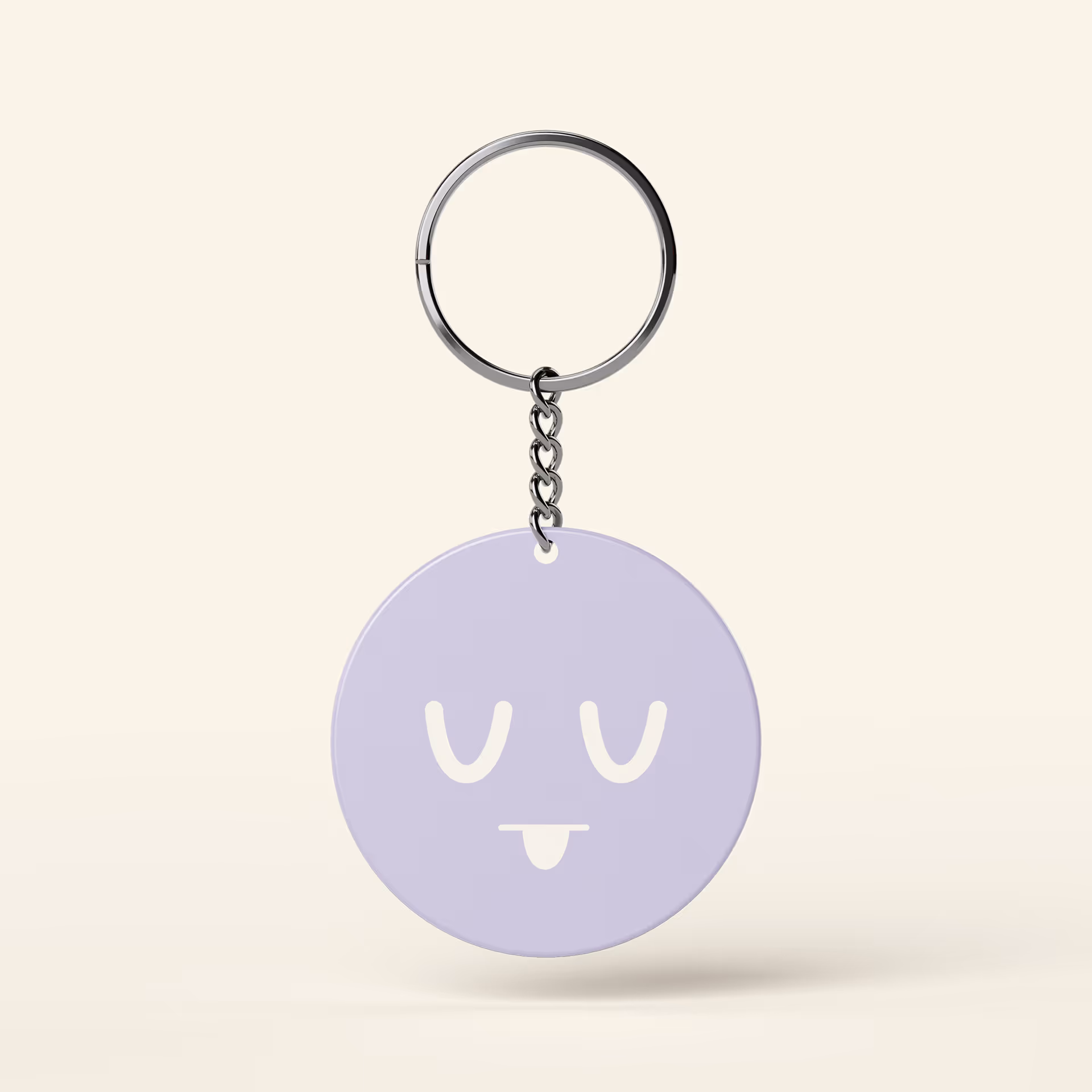 Round lavender keychain with a sleepy face and tongue sticking out on a beige background.