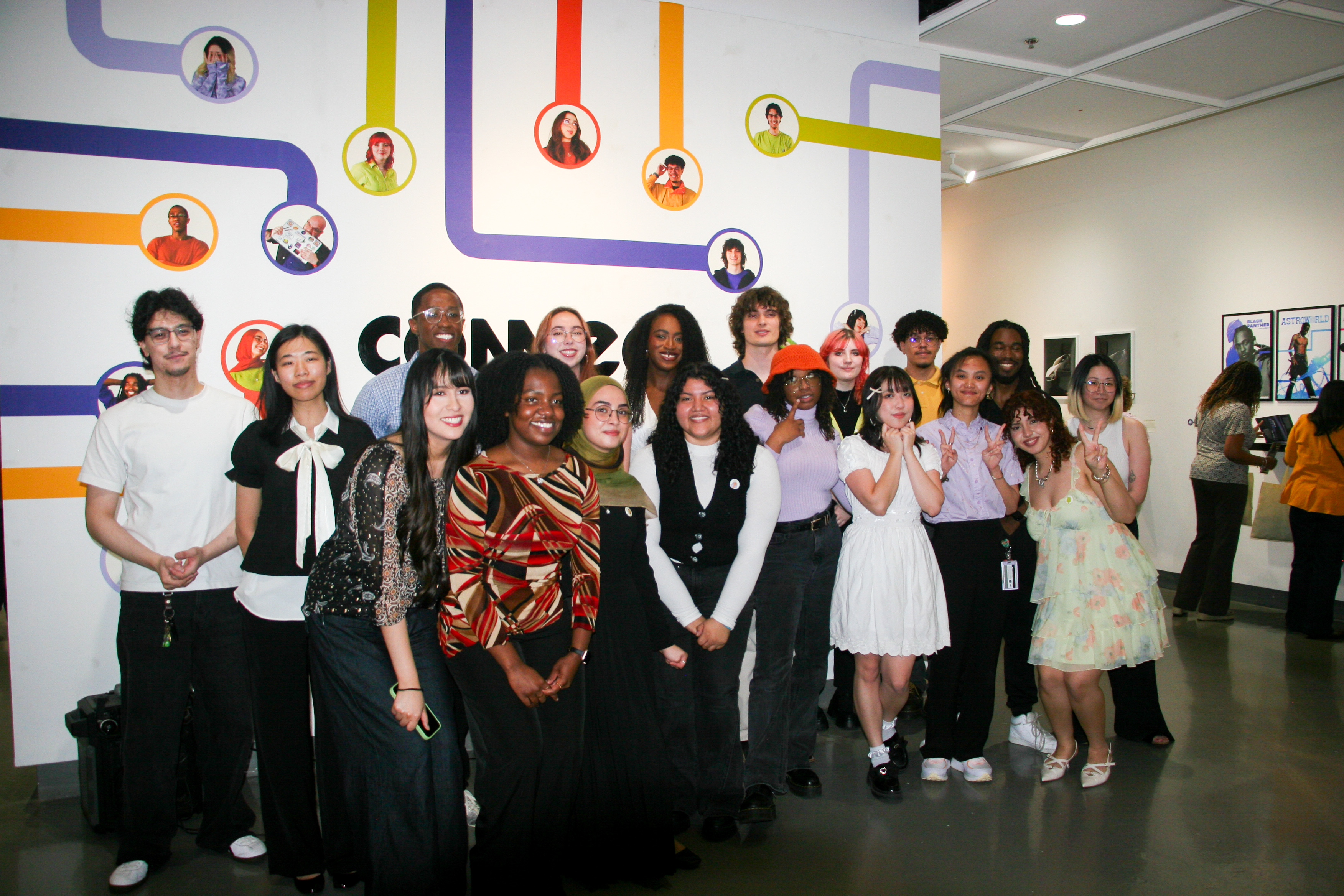 A diverse group of young adults posing and smiling in an art gallery with colorful wall graphics.