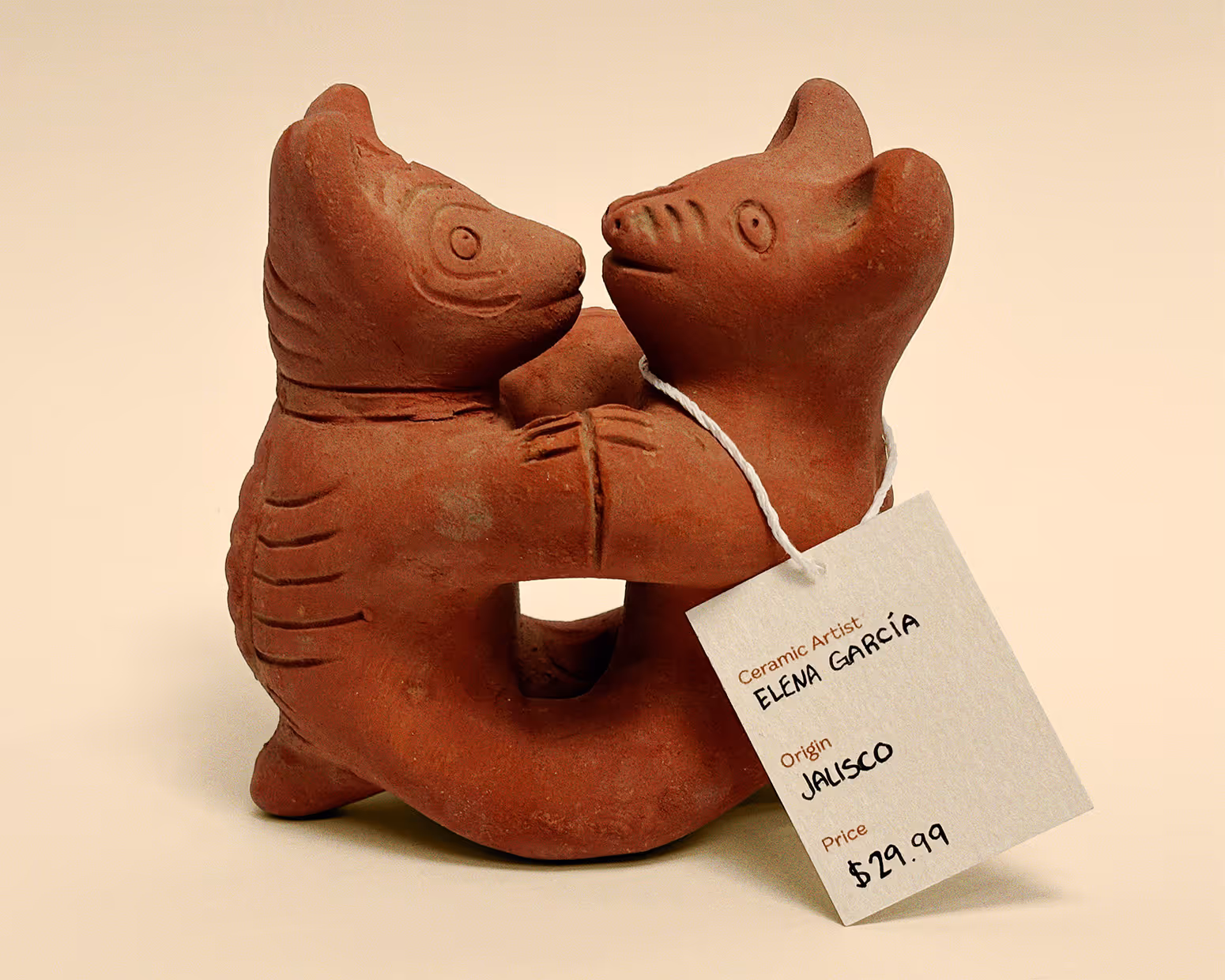 Terracotta ceramic sculpture of two animals hugging with a price tag from Elena Garcia, Jalisco, $29.99.