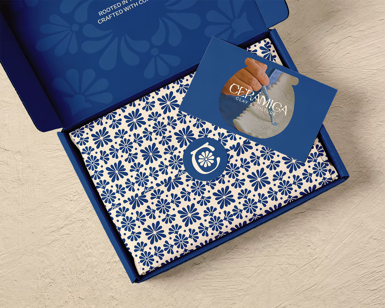 Open blue box with floral patterned wrapping and a card reading Ceramiga Clay & Culture.
