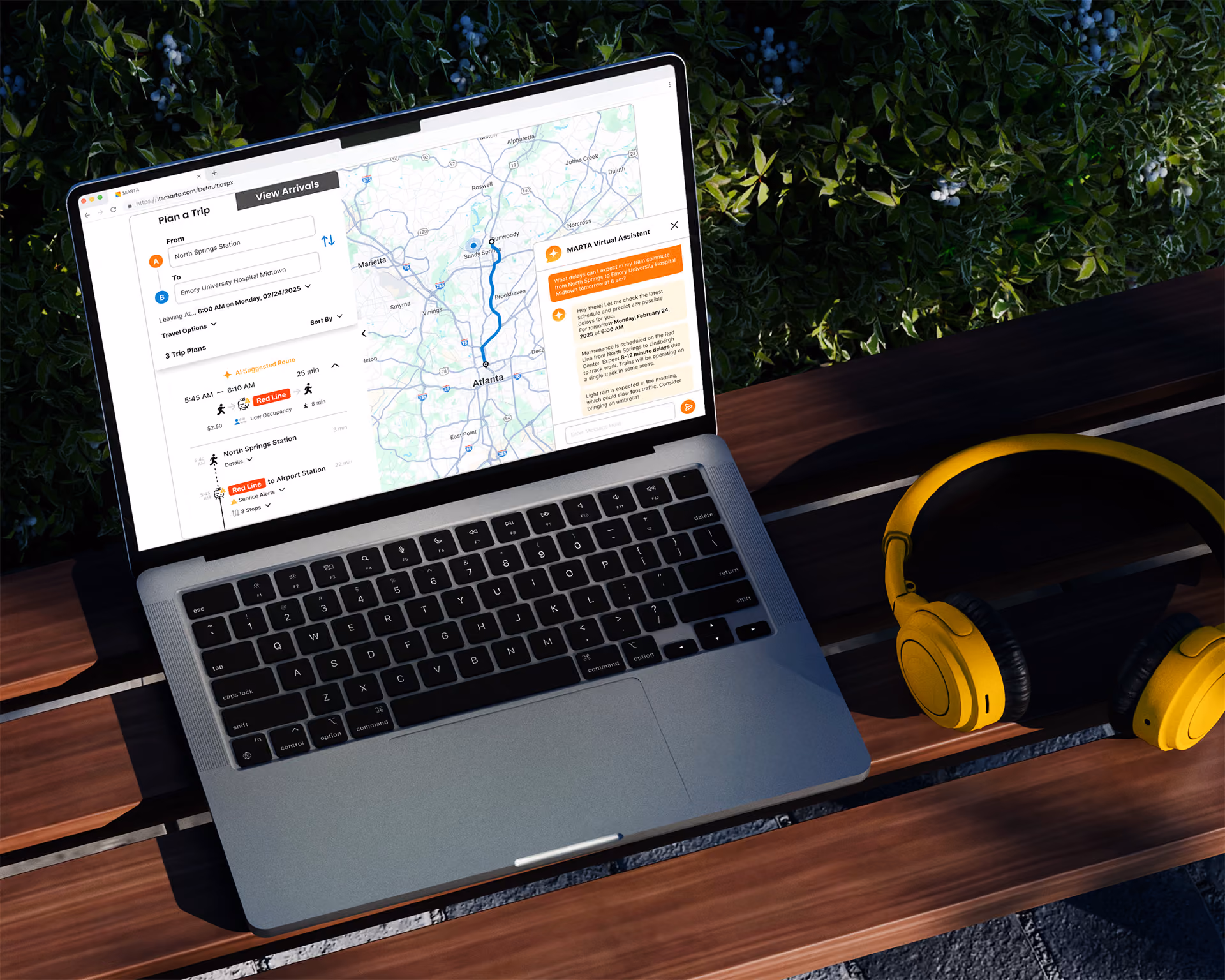 Laptop on wooden bench displays MARTA trip planner with map and virtual assistant chat beside yellow headphones.