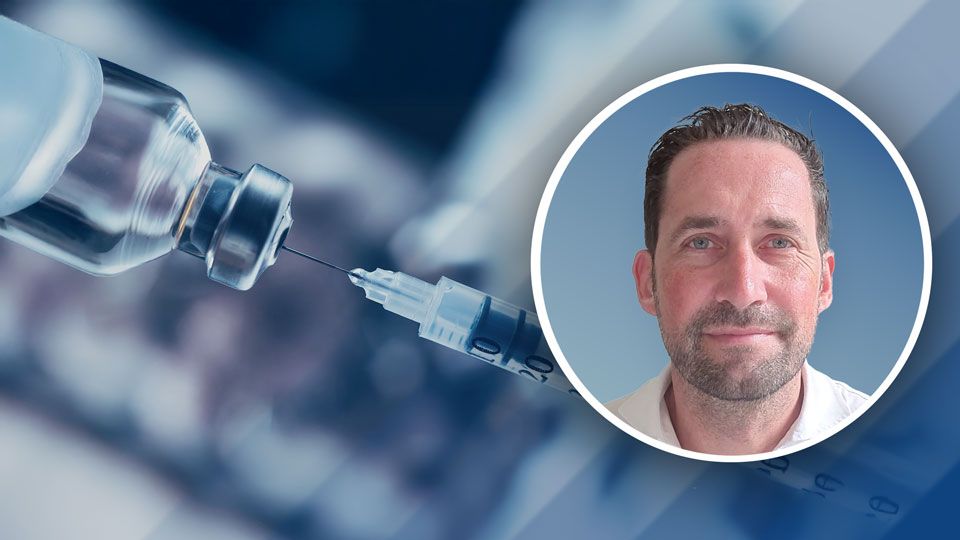 Nahaufnahme einer Impfspritze, die eine Flüssigkeit aus einem Impfstofffläschchen zieht, daneben ein eingefügtes Portrait eines Mannes mit kurzem Haar und Bart vor blauem Hintergrund.