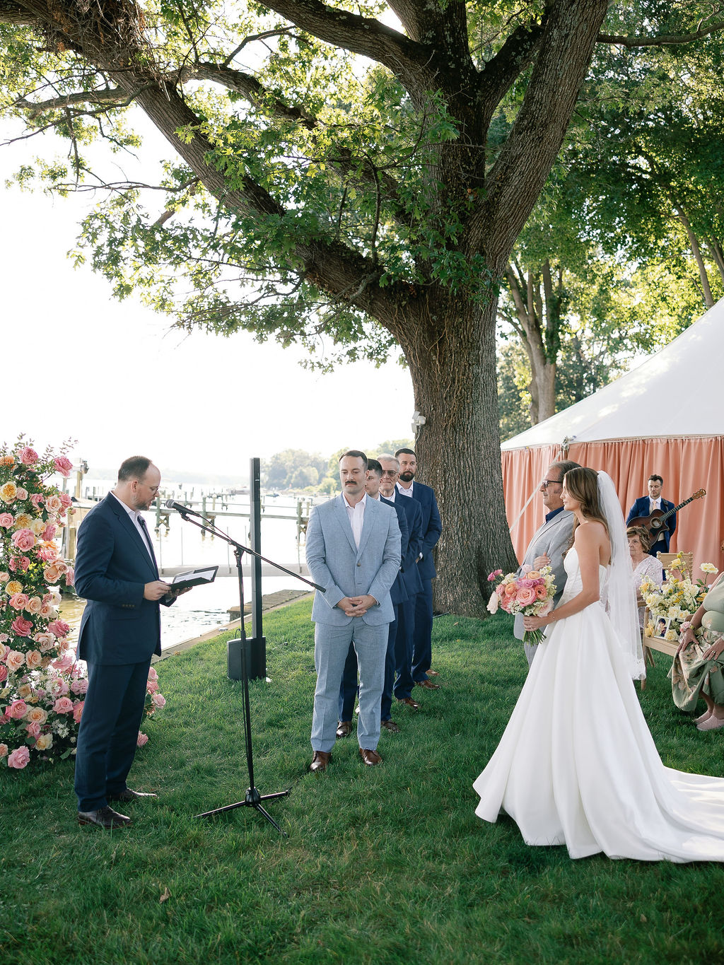 Waterfront wedding ceremony with a live solo guitarist performing in the background.