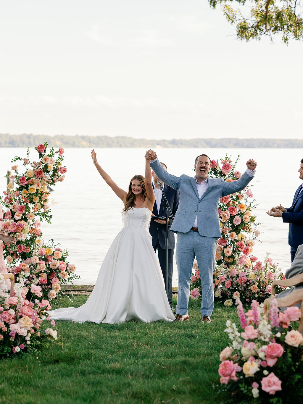 Bride and groom celebrating with raised arms at the end of their ceremony overlooking the water in Lorton, Virginia.