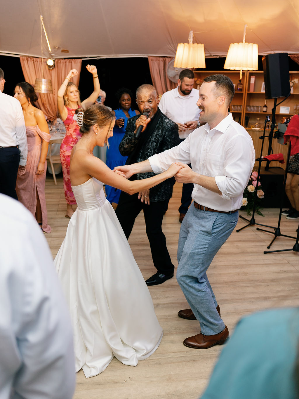 Round Midnight's lead vocalist performing as guests dance under string lights at the reception tent in Lorton, Virginia.