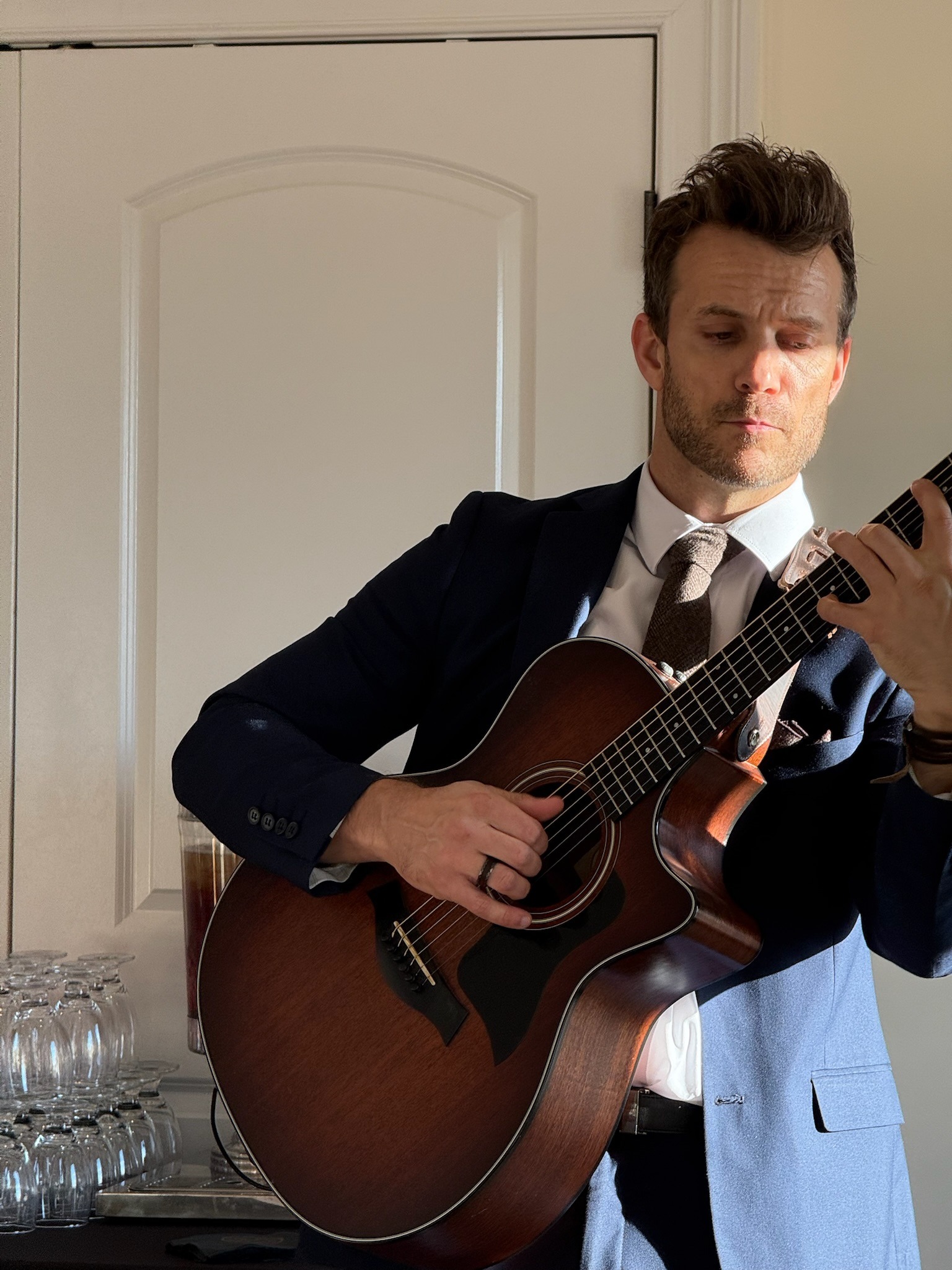 Close-up of Dylan Galvin performing acoustic guitar at a wedding, focused mid-play.