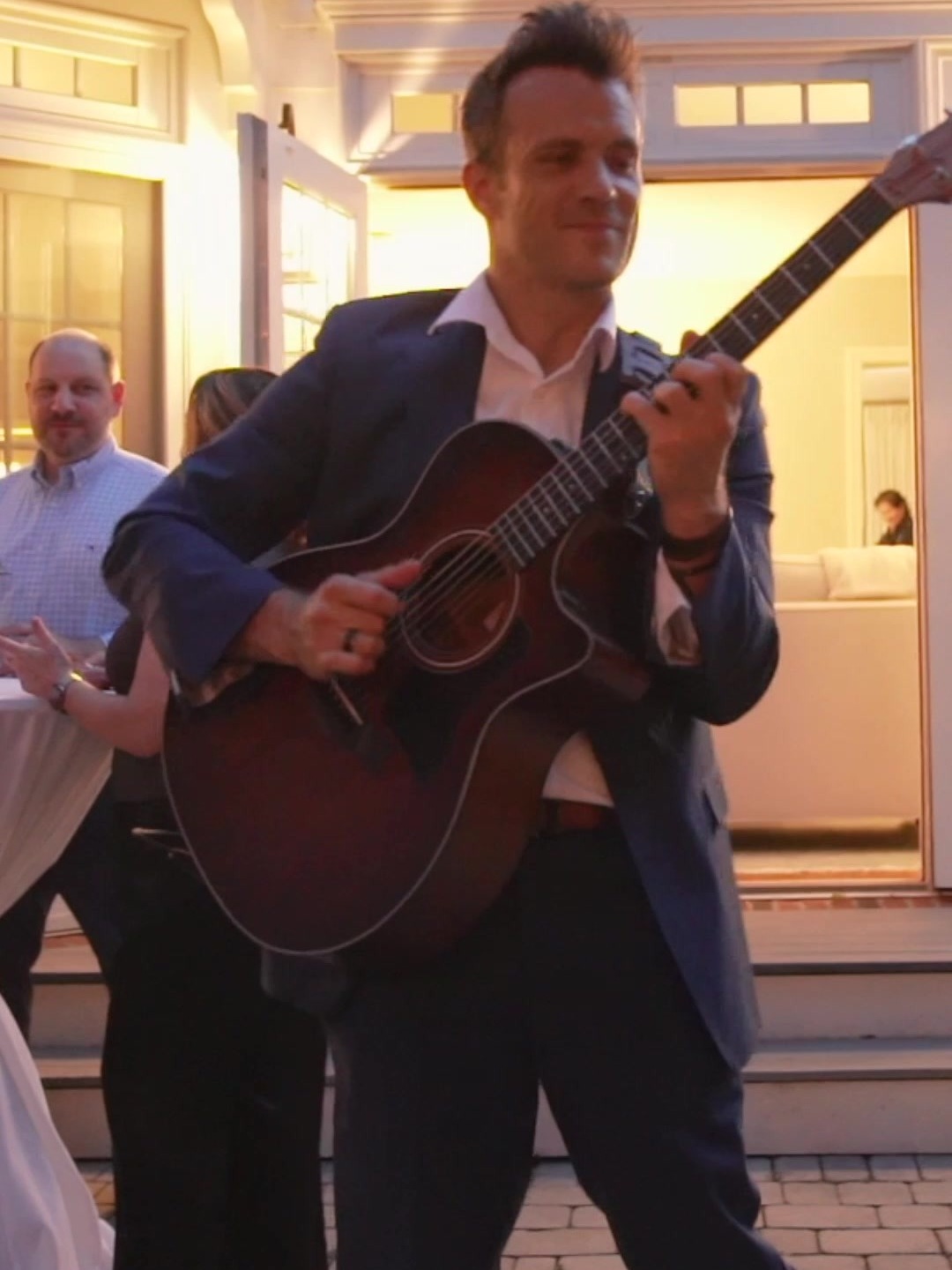 A solo guitarist performing acoustic guitar while roaming among guests at an evening event in Arlington, Virginia.