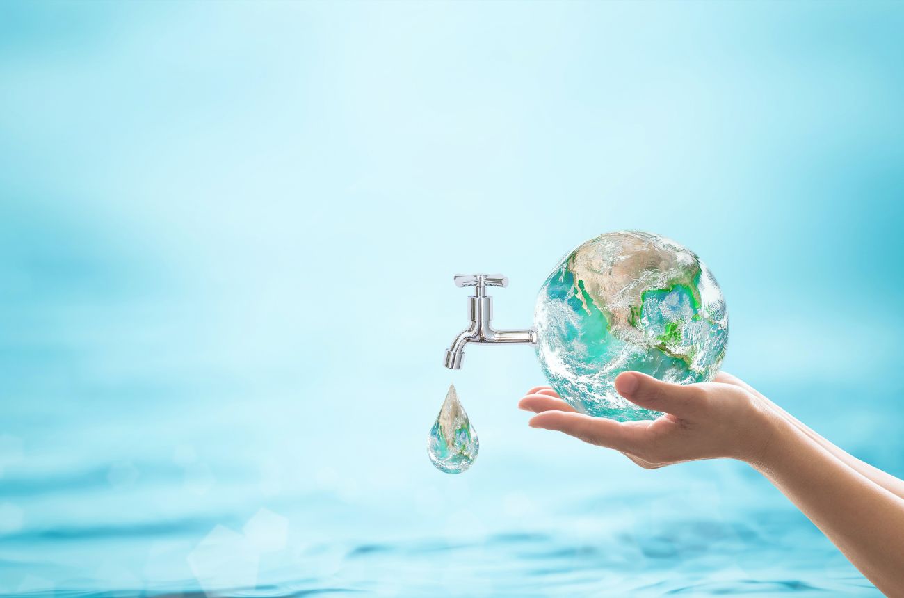 Una mano sosteniendo al planeta tierra, con un fondo azul y que el planeta tierra tiene una llave de la que sale agua