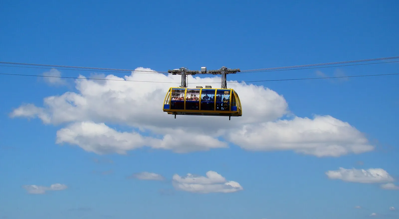 The Scenic Skyway at Scenic World, Blue Mountains, suspended high above with passengers enjoying the view against a backdrop of blue sky and clouds.