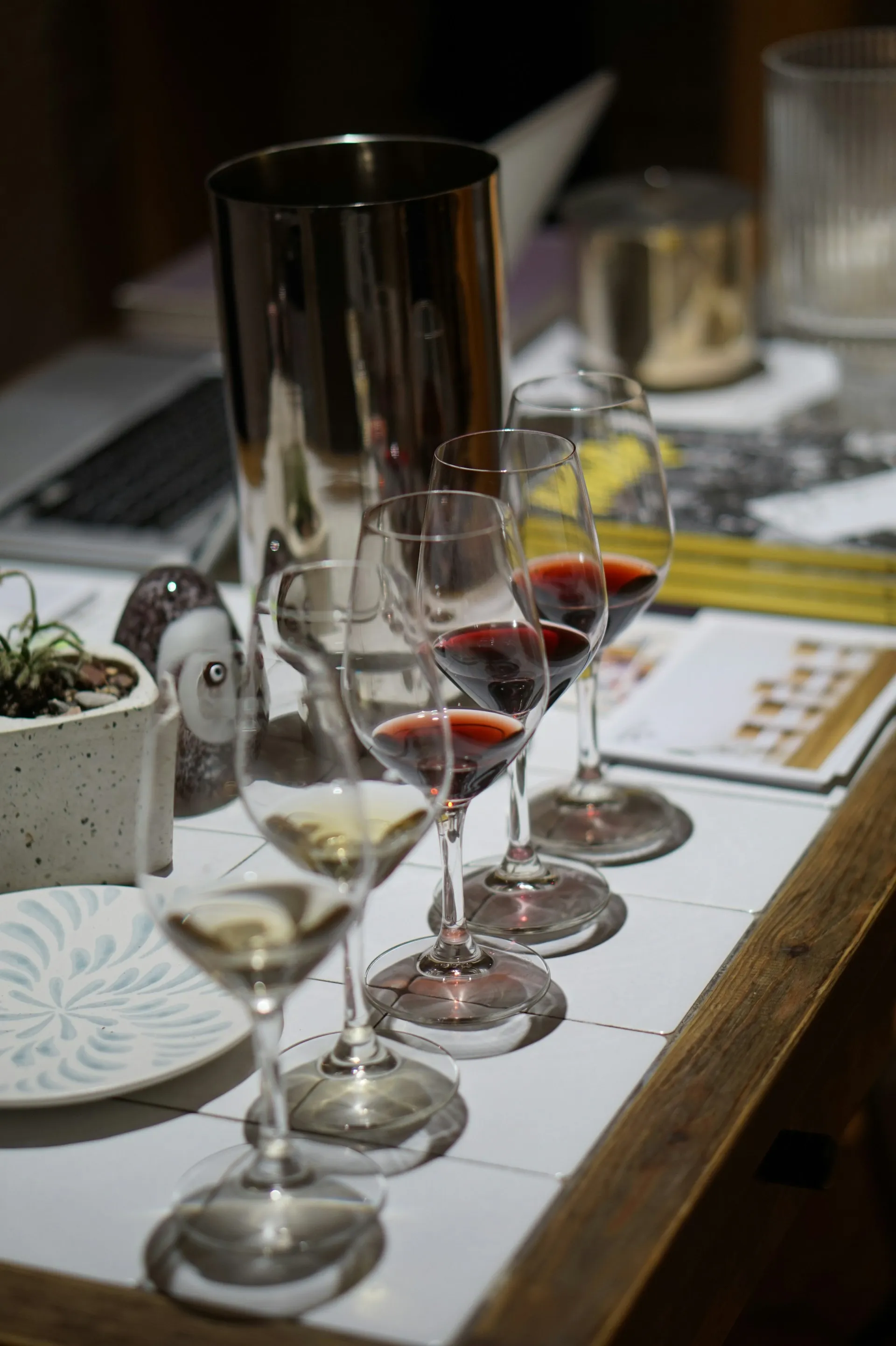 A wine tasting setup featuring multiple wine glasses filled with red and white wine, a spittoon, and decorative items on a table