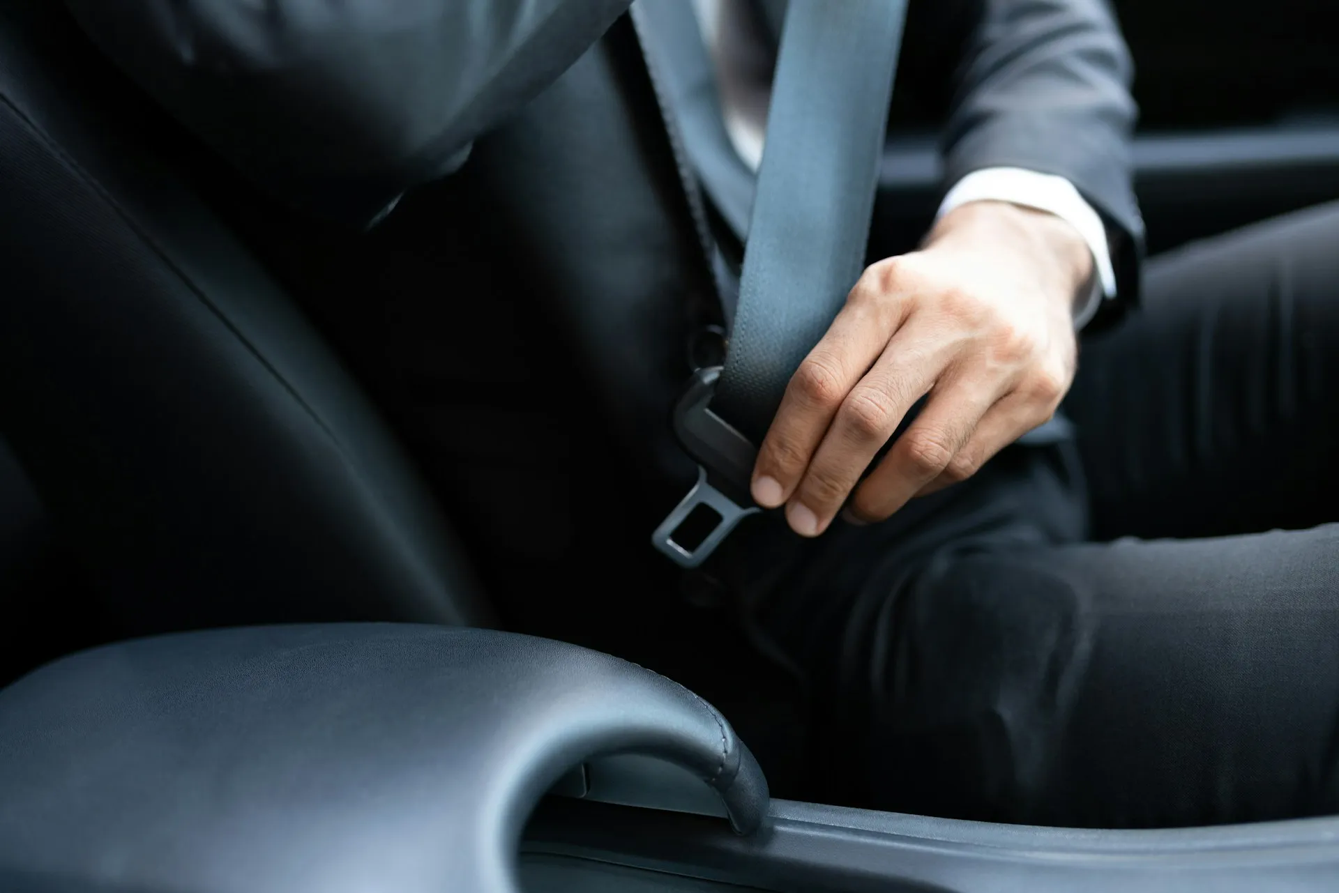 A professionally dressed chauffeur fastening their seatbelt in a premium vehicle, reflecting the safety, reliability, and readiness of Evoke’s guest transport service for seamless event coordination.