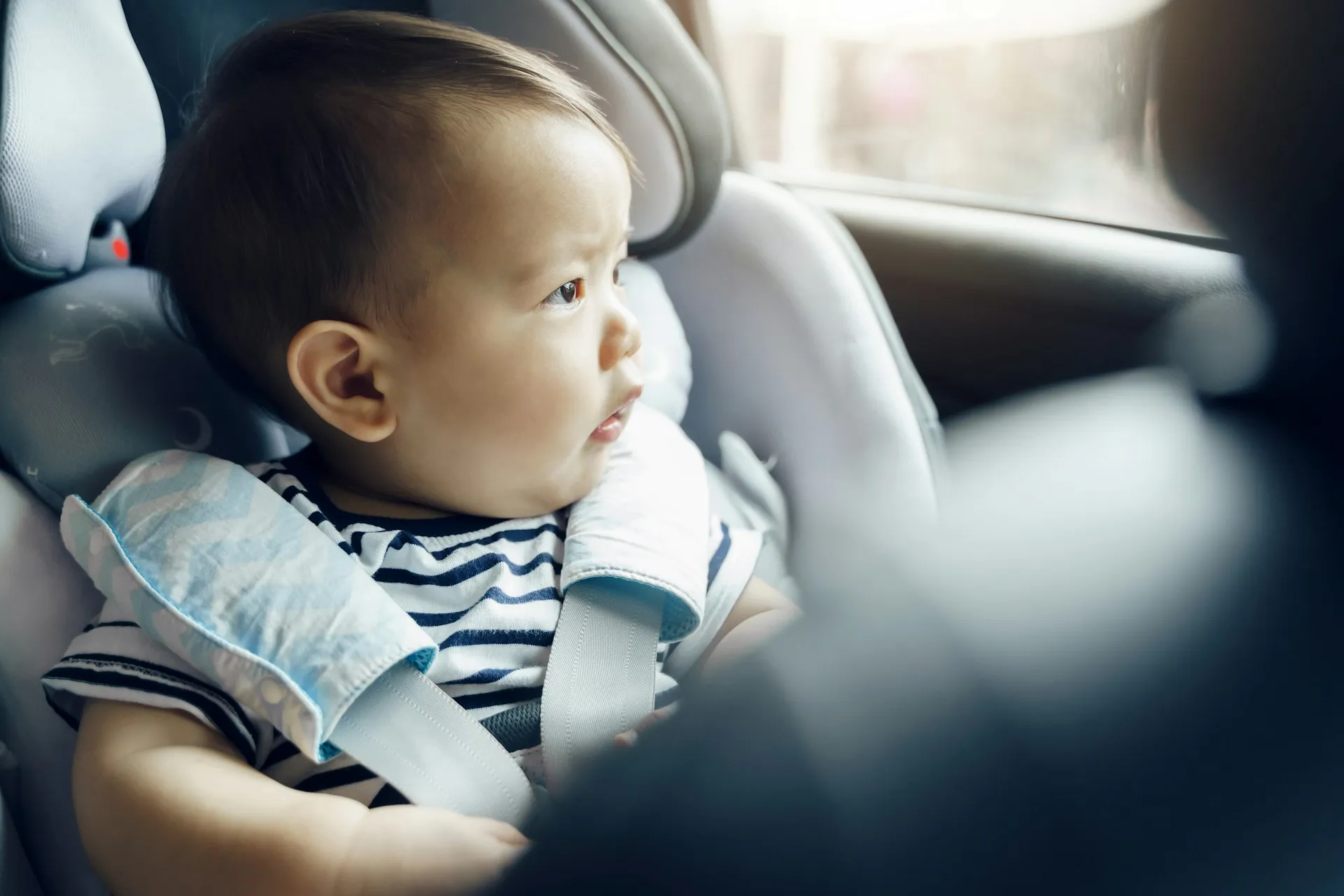 A baby securely fastened in a child safety seat, looking out the window, highlighting Evoke’s commitment to safe, properly equipped transport for even the youngest passengers. Child safety is always our priority.