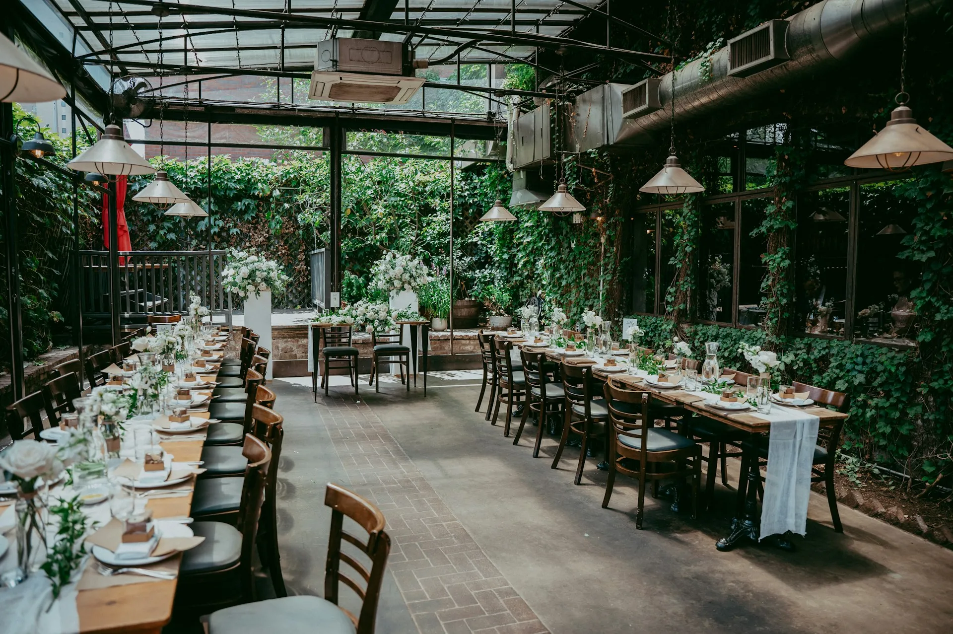 Long tables elegantly set for a special event in a greenery-filled venue.