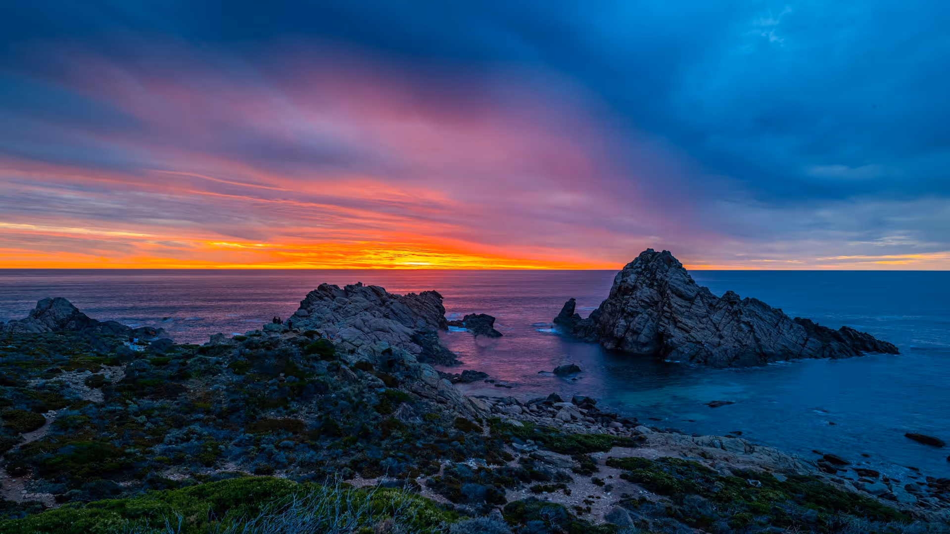 Sunset at Sugarloaf Rock in Margaret River, Western Australia, with vibrant orange and pink skies over the ocean.