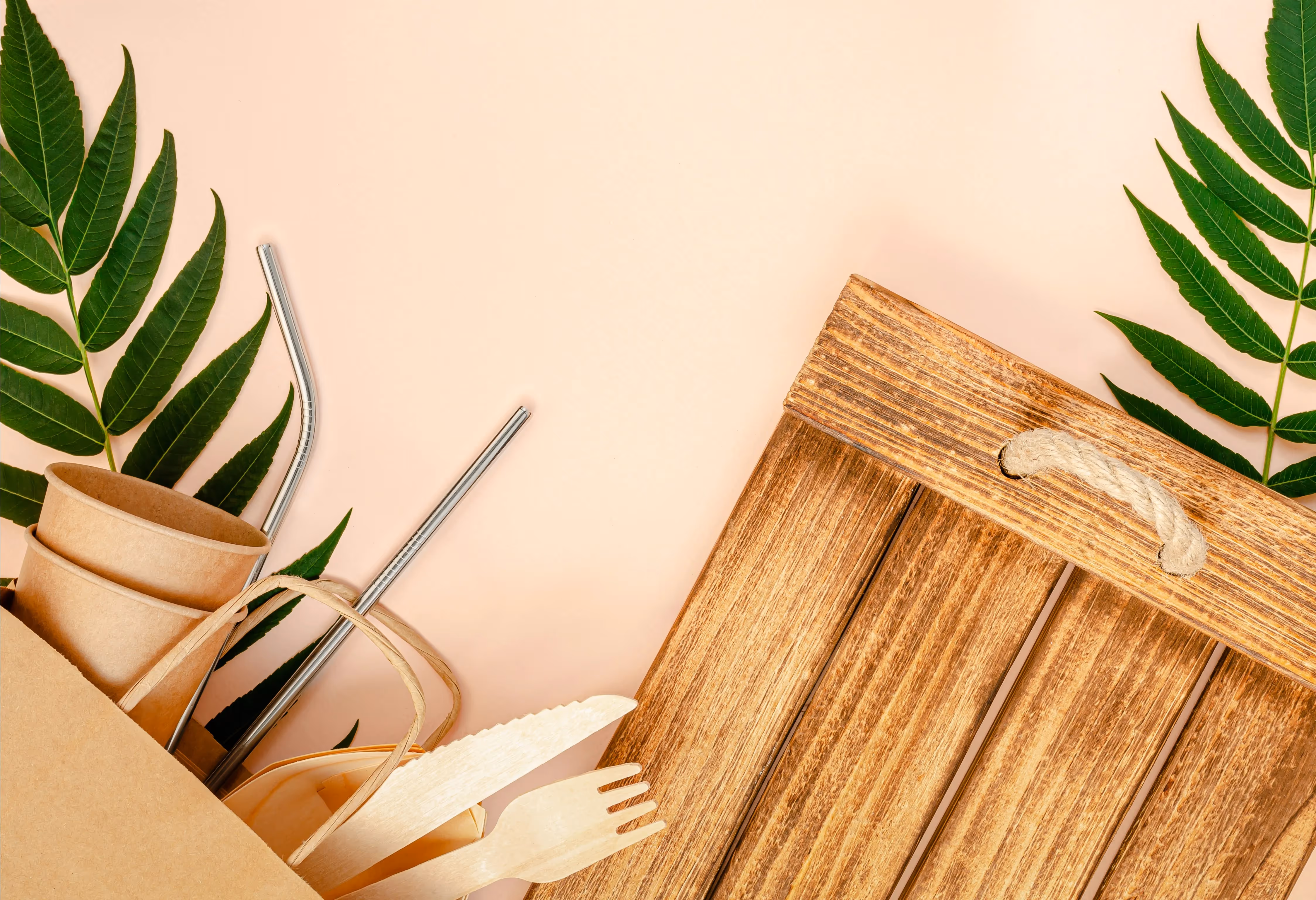 Reusable and eco-friendly utensils, cups, and straws displayed on a wooden tray, symbolising sustainable, plastic-free living.