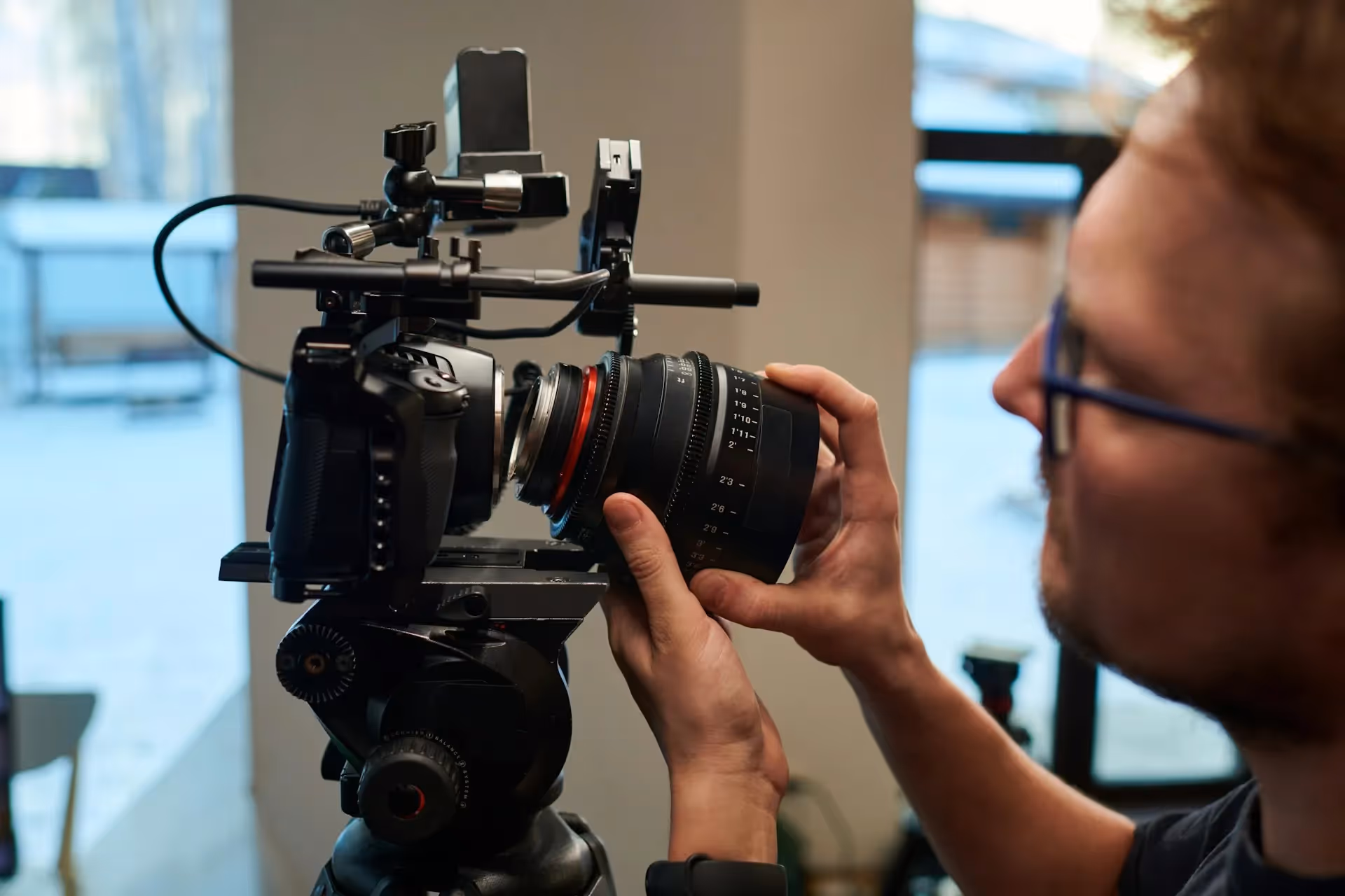 A person adjusting the lens of a professional video camera on a tripod.