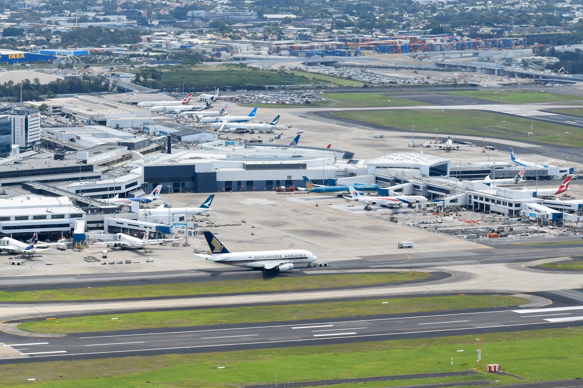Aerial view of Sydney Airport with various aircraft on the runways and terminals.