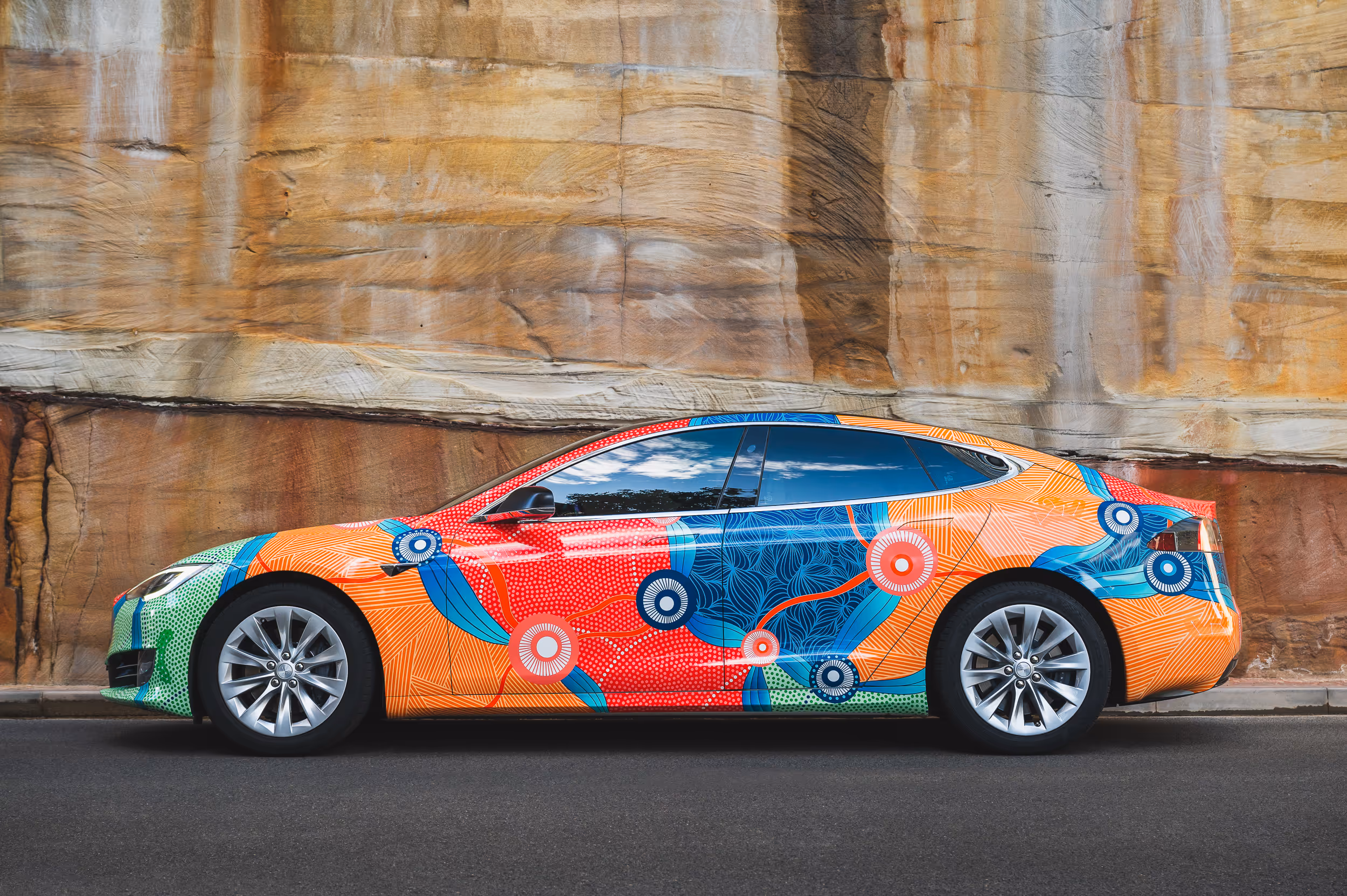 Side view of "Art Car" against sandstone background, showcasing First Nations artwork.