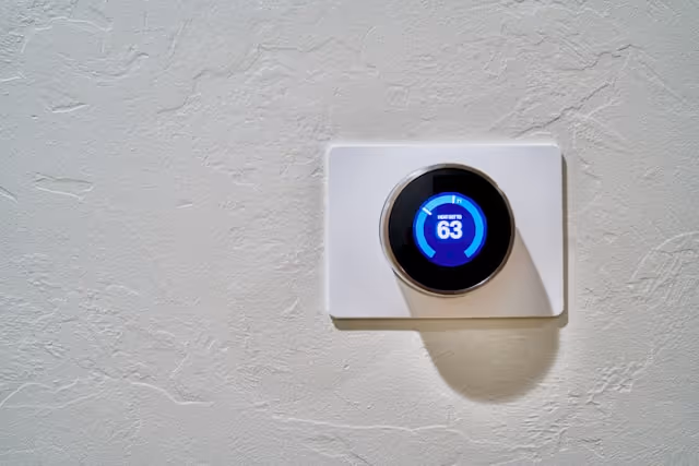 A programmable thermostat mounted on a white wall.